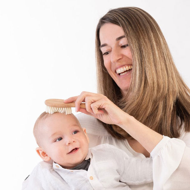 Ein Baby wird mit der Babyhaarbürste sanft gekämmt